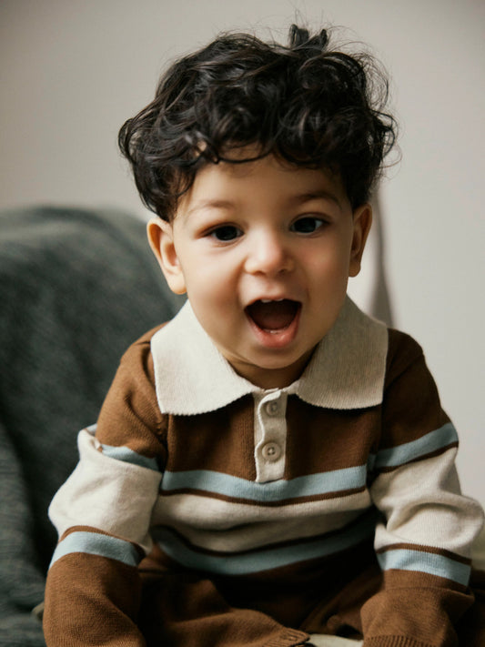 Ral brunrandig stickad babyoverall från Name It med beige pikékrage och knappar framtill.