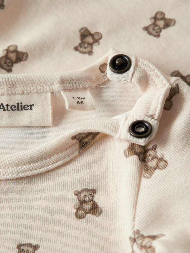 Lil' Atelier beige body med nallemönster för baby unisex i ekologisk bomull och TENCEL™ Lyocell med tryckknappar och mjuk stretchkvalitet
