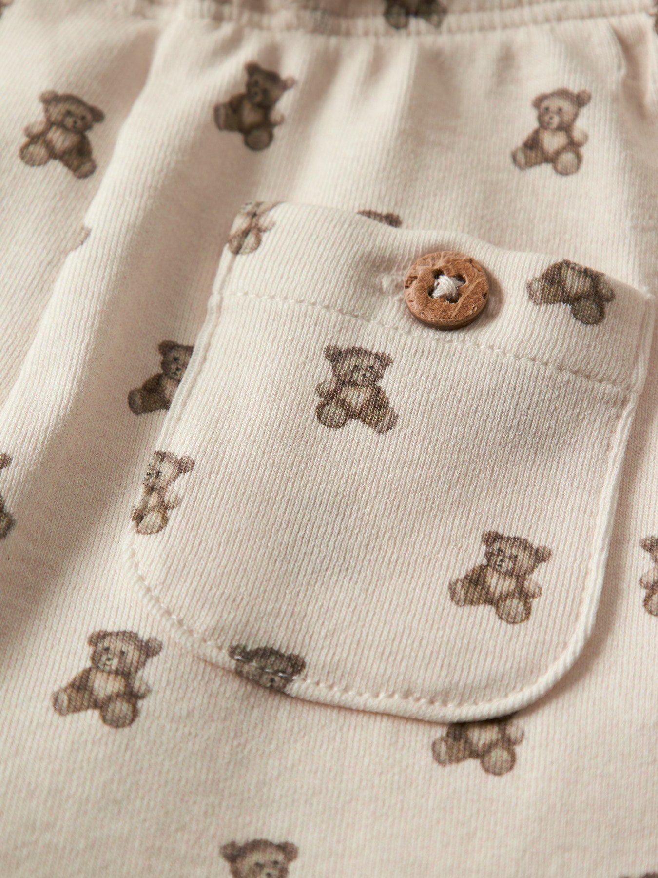 Lil' Atelier beige babybyxa till pojke och flicka med nallemönster, reglerbar midja och mjuk jerseykvalitet