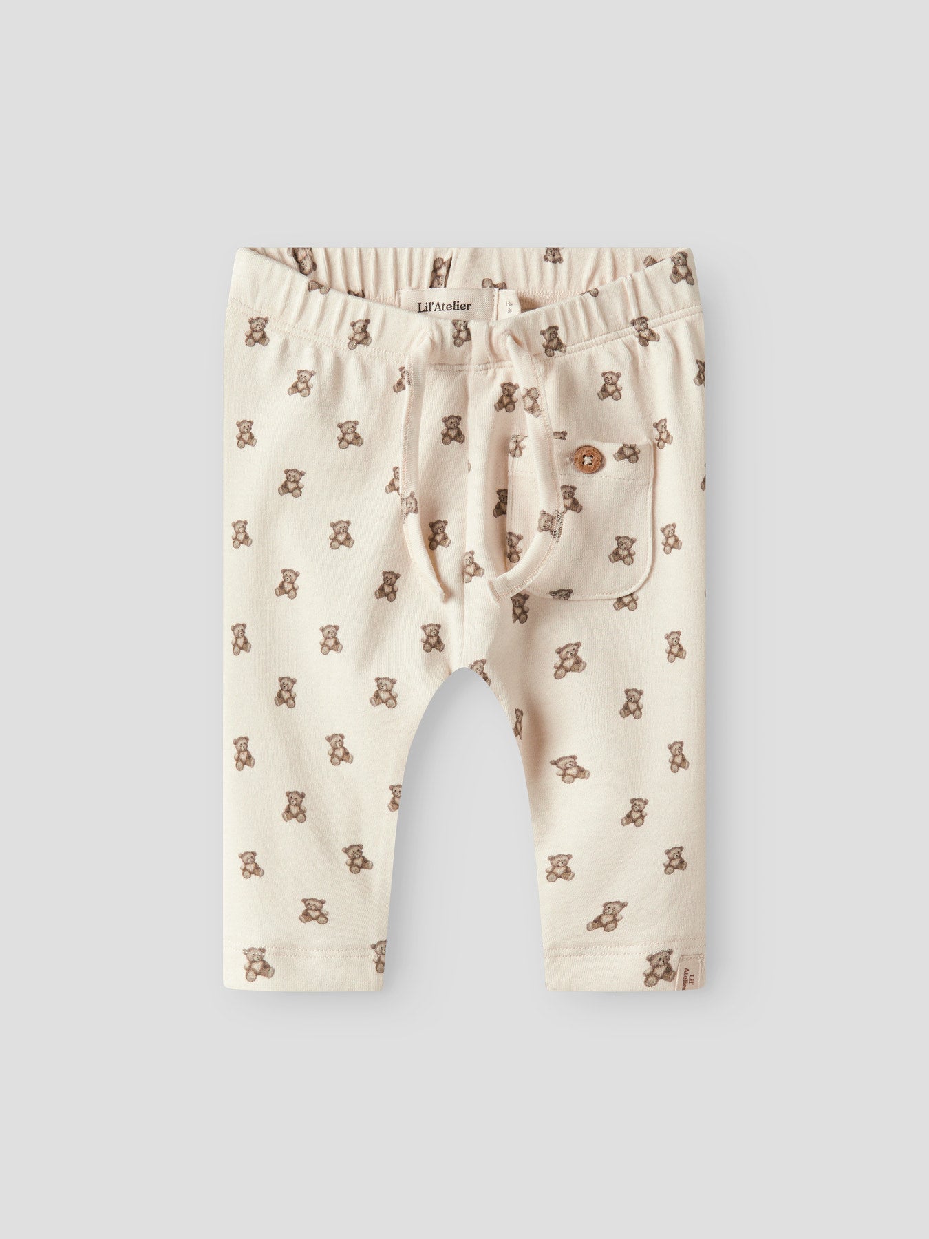 Lil' Atelier beige babybyxa till pojke och flicka med nallemönster, reglerbar midja och mjuk jerseykvalitet