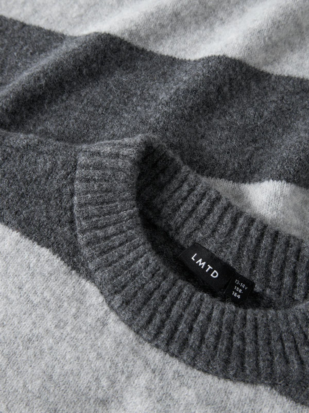 LMTD Bynthe randig stickad tröja för ungdomstjej i mörkgrå nyanser med lång ärm och mjuk fluffig kvalitet. Modell NLFBYNTHE STRIPE LS SHORT KNIT NOOS.