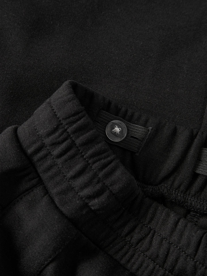 Svarta wide leg sweatpants till flicka från name it med dekorativa tryckknappar längs sidorna, sidofickor och justerbar midja.