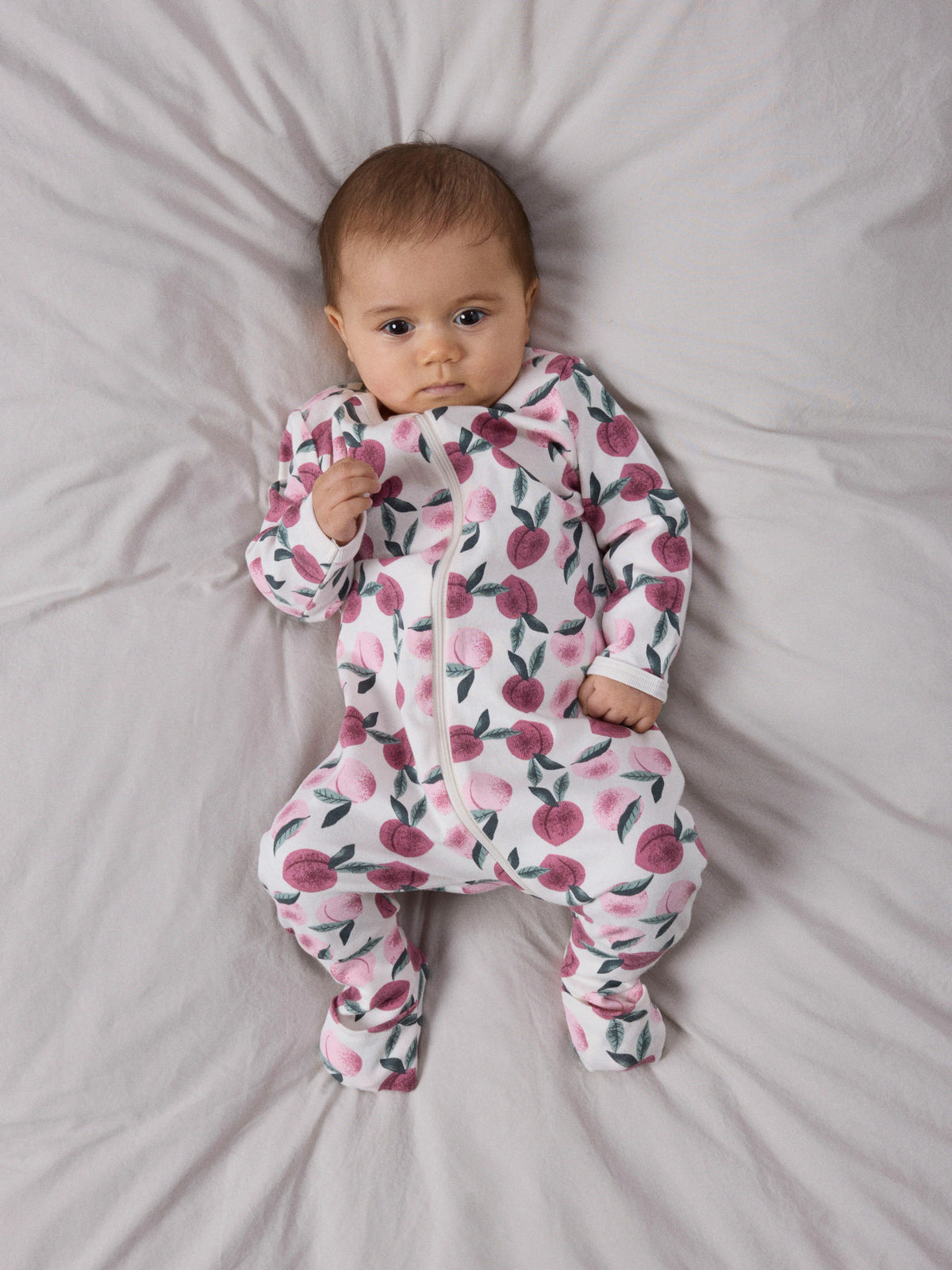 Name It baby pyjamas med valfri fot i färgen Jet Stream med rosa persikor, långärmad pyjamas med tvåvägsdragkedja för baby flicka.