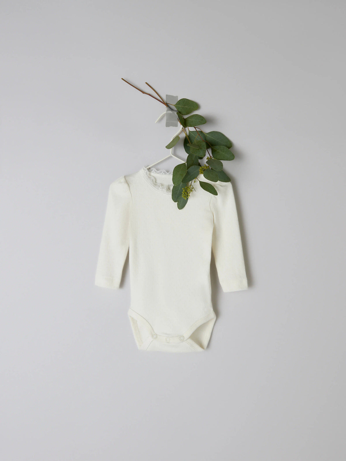 Name It Nia vit långärmad babybody med spetskant till nyfödd flicka.