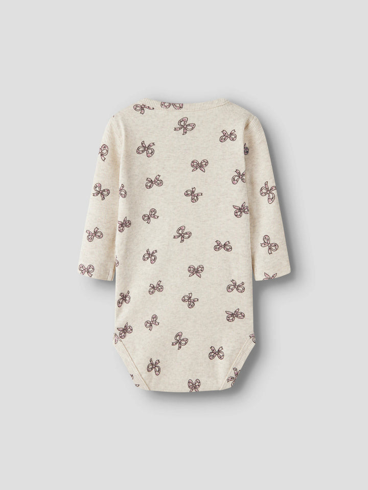 Rulies långärmad ribbad babybody för flicka från Name It i ljusbeige med små rosa rosetter och tryckknappar i grenen.
