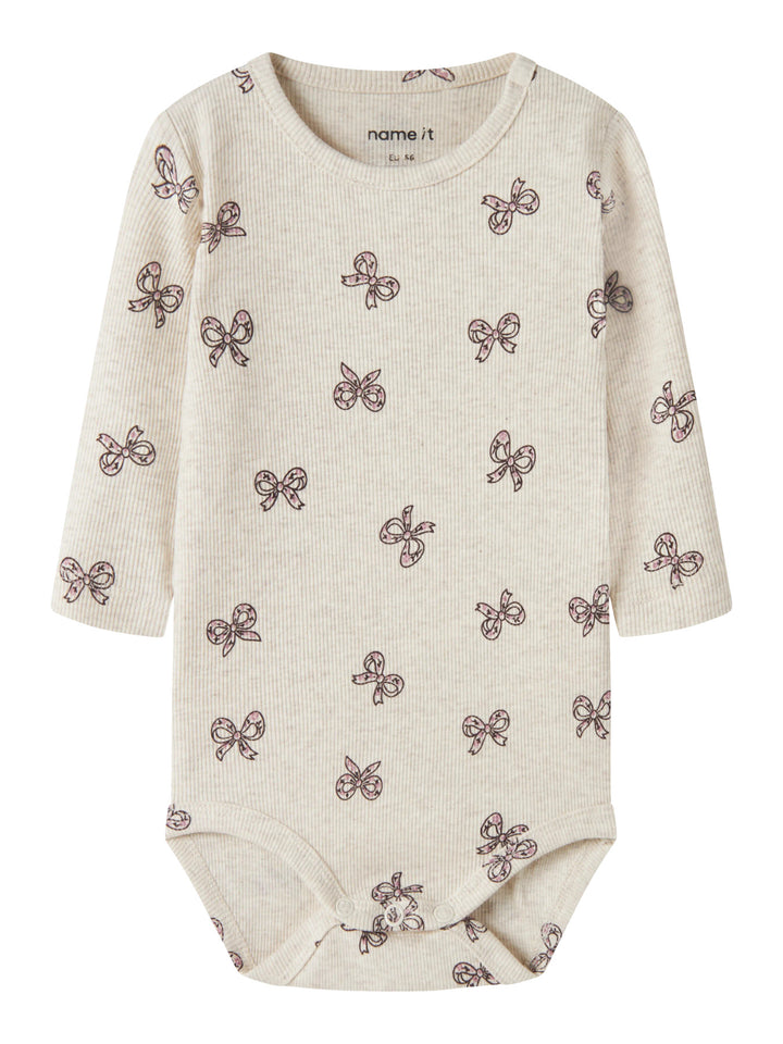 Rulies långärmad ribbad babybody för flicka från Name It i ljusbeige med små rosa rosetter och tryckknappar i grenen.