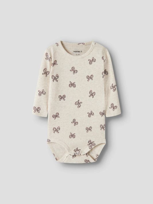 Rulies långärmad ribbad babybody för flicka från Name It i ljusbeige med små rosa rosetter och tryckknappar i grenen.