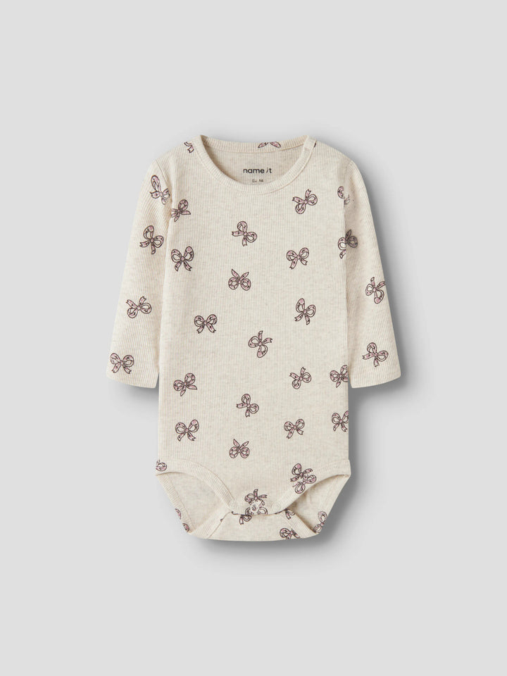 Rulies långärmad ribbad babybody för flicka från Name It i ljusbeige med små rosa rosetter och tryckknappar i grenen.