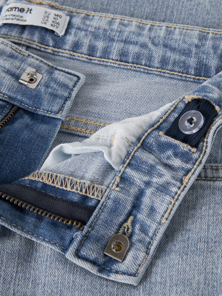 Närbild på fransig V-formad detalj på bakfickan på Polly jeans