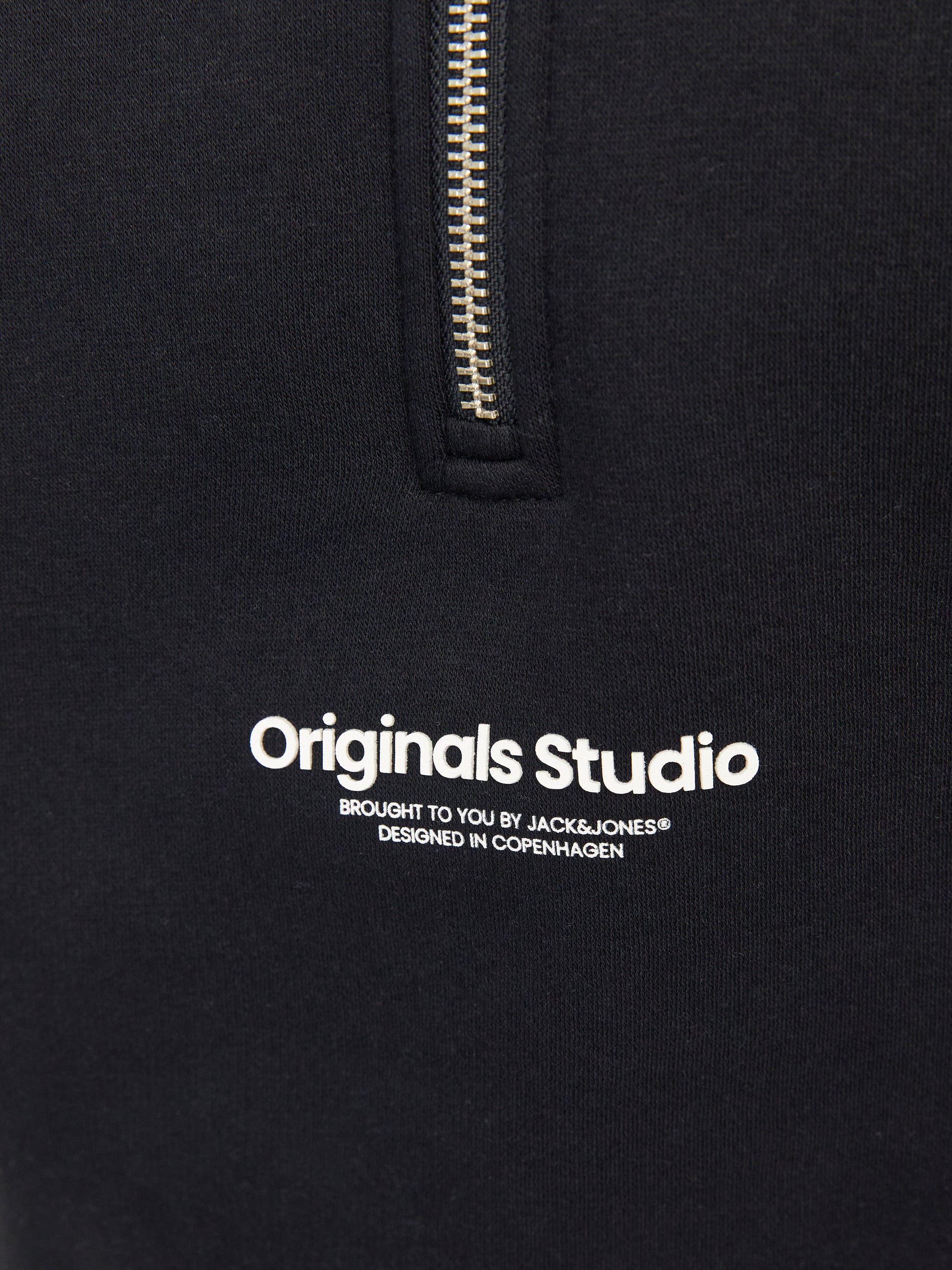 Närbild på logga origials studio. Snygg svart zip tröja till ungdom kille från Jack & Jones. Sweatshirt med hög hals och dragkedja till pojke teen. Vestrebro.