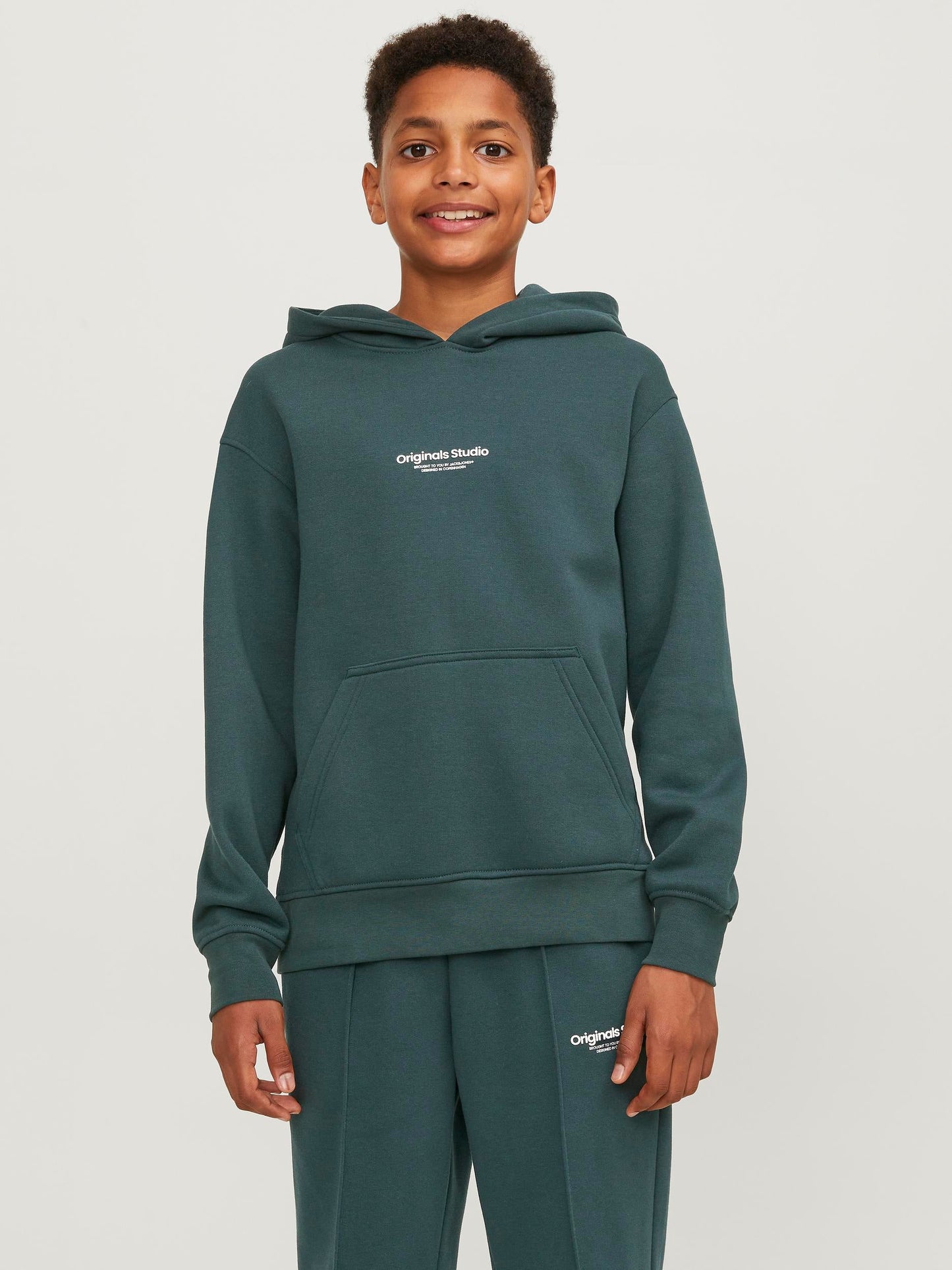 Kille klädd i luvtröja, Hoodie från Jack & Jones i mörk grön färg. Tröja till ungdom kille, pojke.
Ingen garderob är komplett utan några pålitliga plagg som luvtröjor och andra sweatshirts. Borstad tyg med mjuk finish på insidan. Lätt borstade tyger definieras av att insidan av tyget har en lätt hårig textur och en mjuk känsla.

Produkttyp: Hoodie
Hals: Hoodie
Ärm: Lång ärm
Ärmar: Sätt i ärmar
Fickor: Känguruficka
Foder: tyg inuti huvan
Print : 3D-utskrift för en tredimensionell look
Kroppstyp: Junior