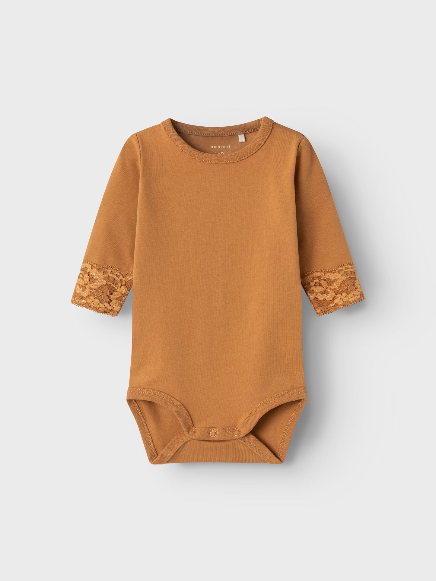 Långärmad body med söt spetskant vid handen. Ekologisk baby body i fin brun färg. Bebiskläder, bodysuit.