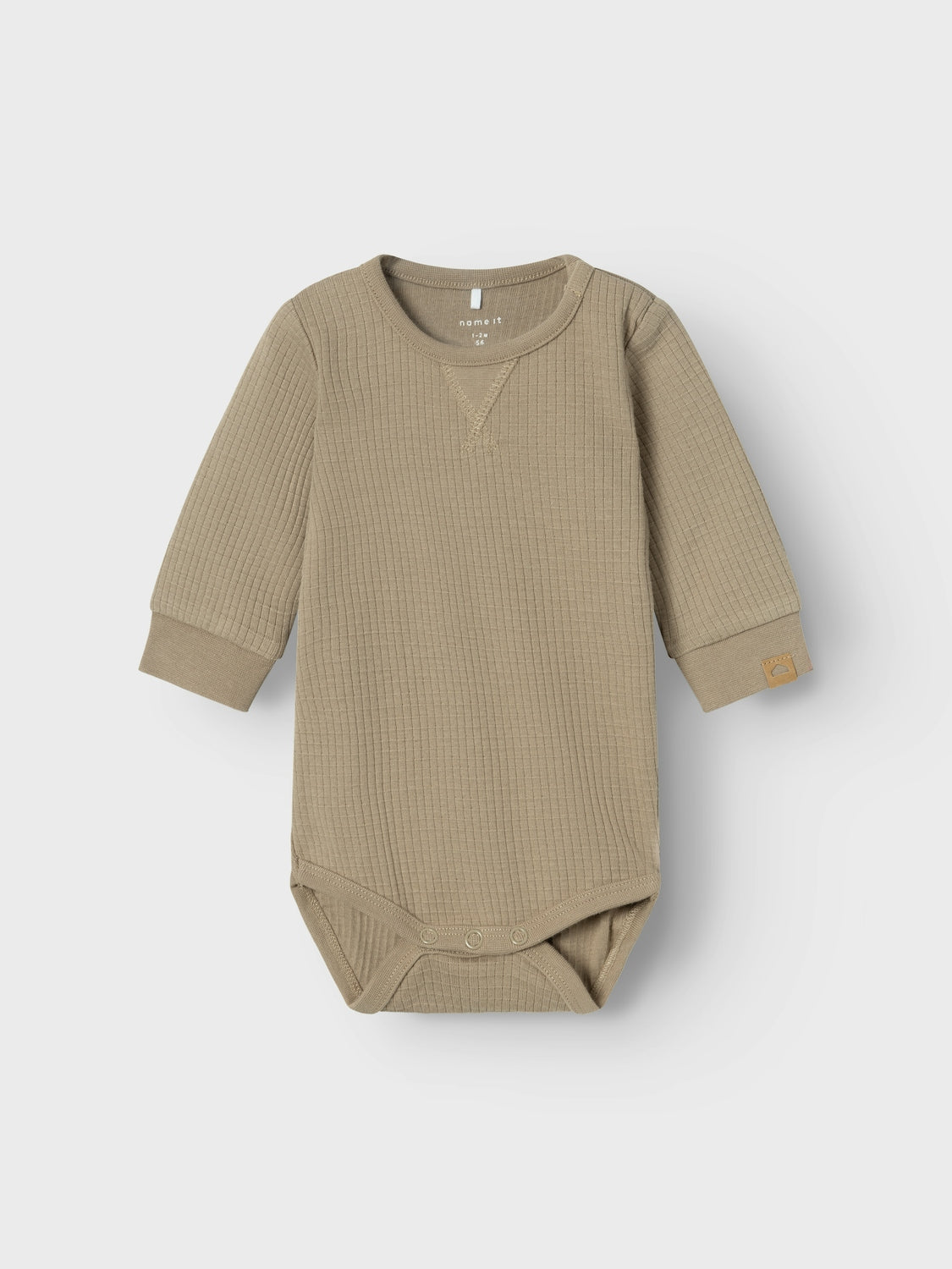 Enfärgad beige body i ekologisk bomull till din baby pojke. Långärmad body till din lille kille. Fräscha upp ditt barns garderob med mjuka och praktiska bodys som är perfekta att använda året runt. Ribbstickad har ett vertikalt, randigt mönster och bra elasticitet för en skön känsla och en tidlös look.

Produkttyp: Bodysuit
Hals: Rund hals
Ärm: Lång ärm
Stängning: Tryckknapp
Extra detaljer: Badge