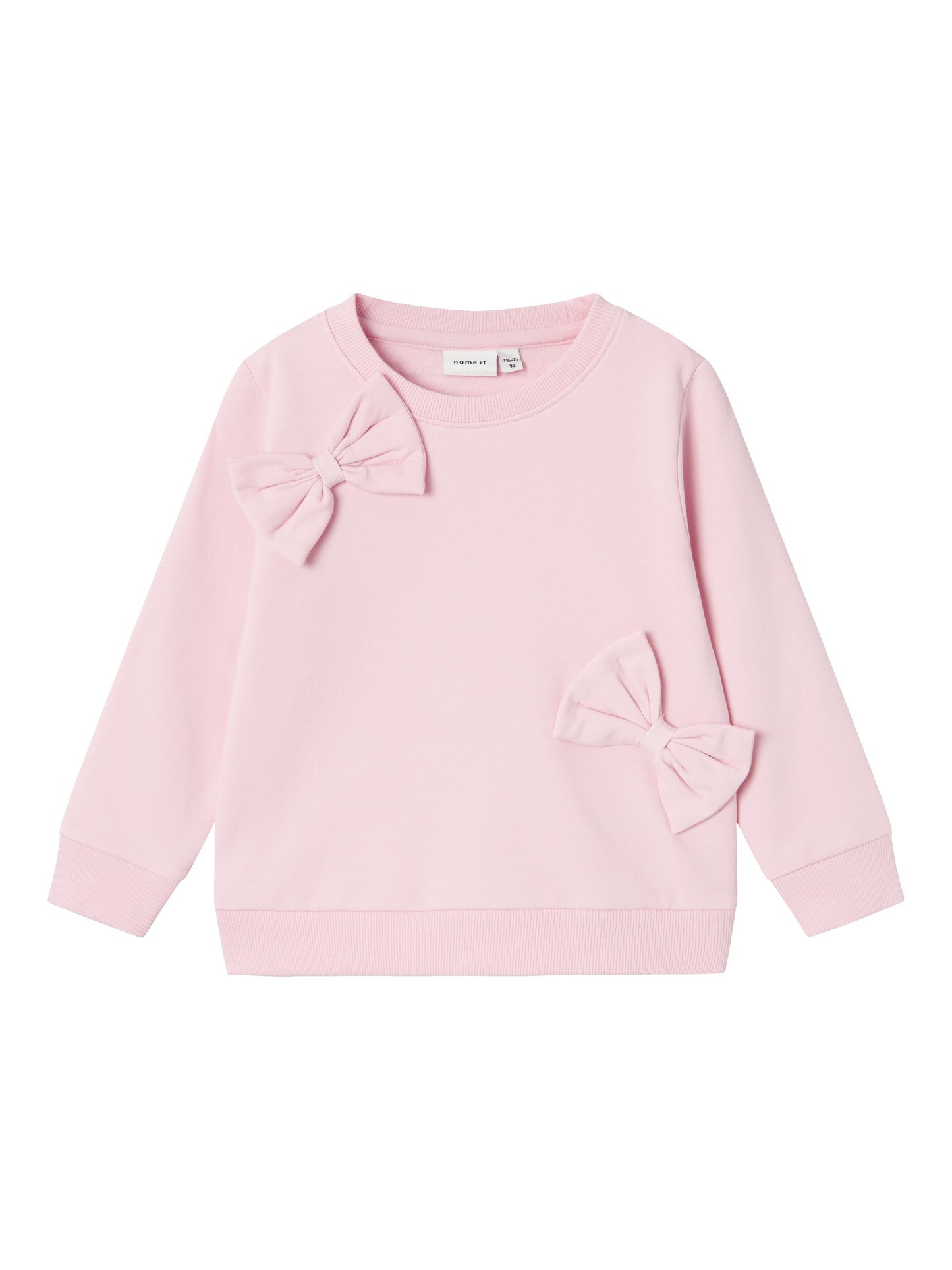 Söt enfärgad rosa sweatshirt tröja med stora rosetter till flicka, tjej.
Välkommen bekväma och coola sweatshirts till ditt barns garderob och skapa en trendig och avslappnad look. Borstad sweatshirt i ekologisk bomull har en mjuk insida för en bekväm känsla till ditt barn.

Produkttyp: Sweatshirts
Hals: Rund hals
Ärm: Långa ärmar
Muddar: Ribbstickade muddar
Extra detaljer : Bowdetalj, 3D-detalj
Passform: Normal passform