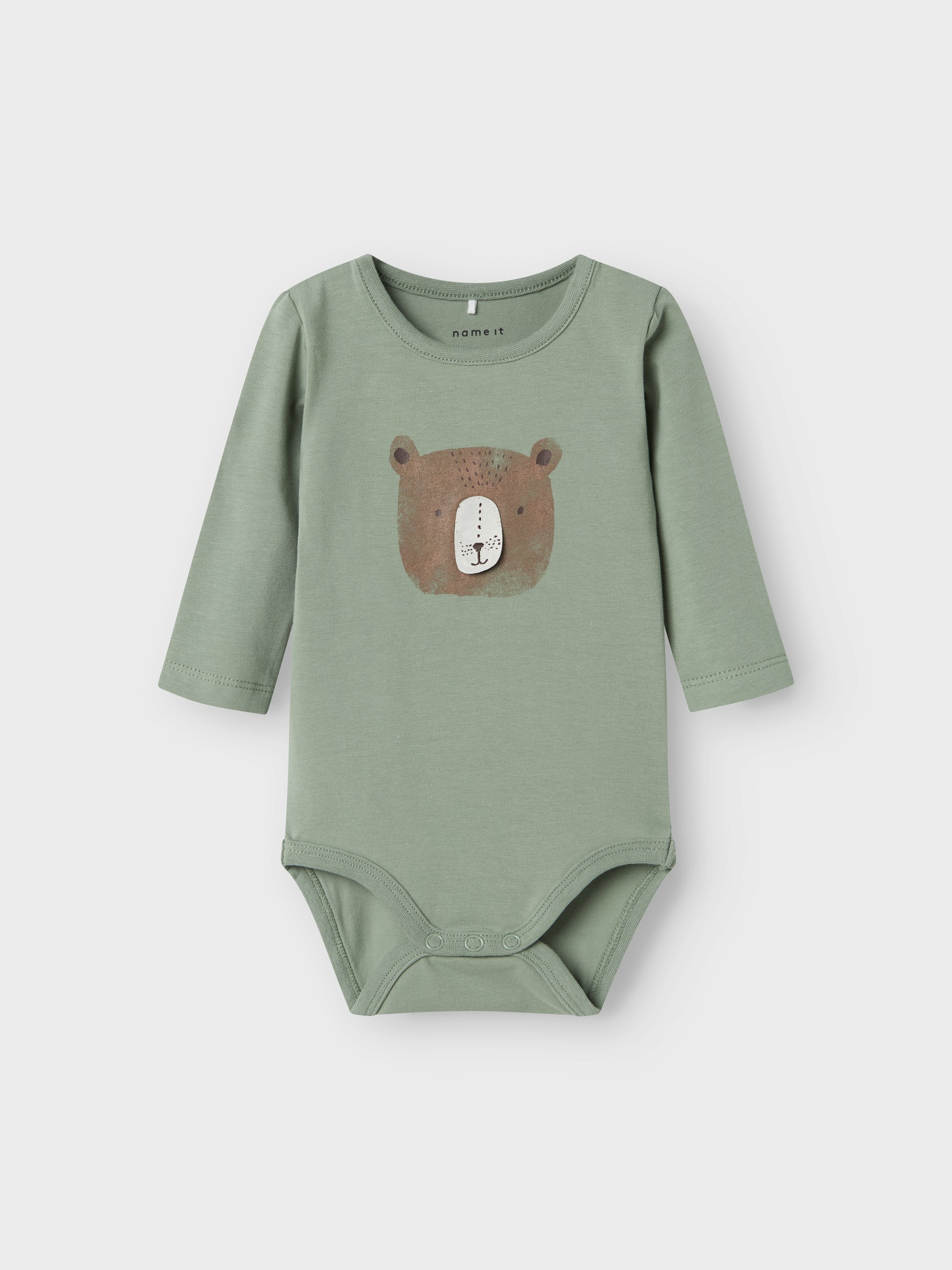 Grön body till baby pojke med en björn på magen. Väldigt söt överdel i ekologisk bomull.

Produkttyp: Bodysuit
Hals: Rund hals
Ärm: Lång ärm
Stängning: Tryckknapp
Extra detaljer: 3D-detalj