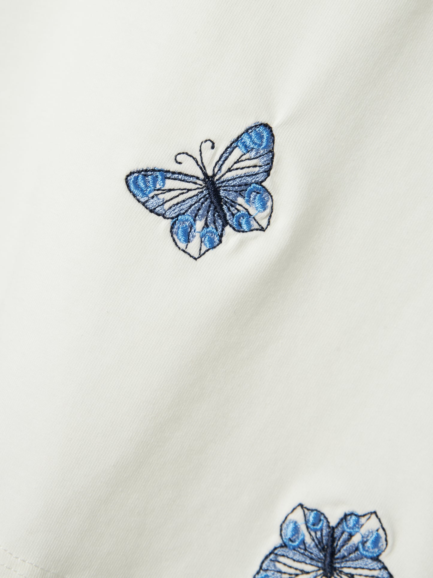Kortärmad vit t-shirt med broderade fjärilar till flicka. Ekologiska barnkläder från Name it.
NMFDENYS SS TOP
13241021